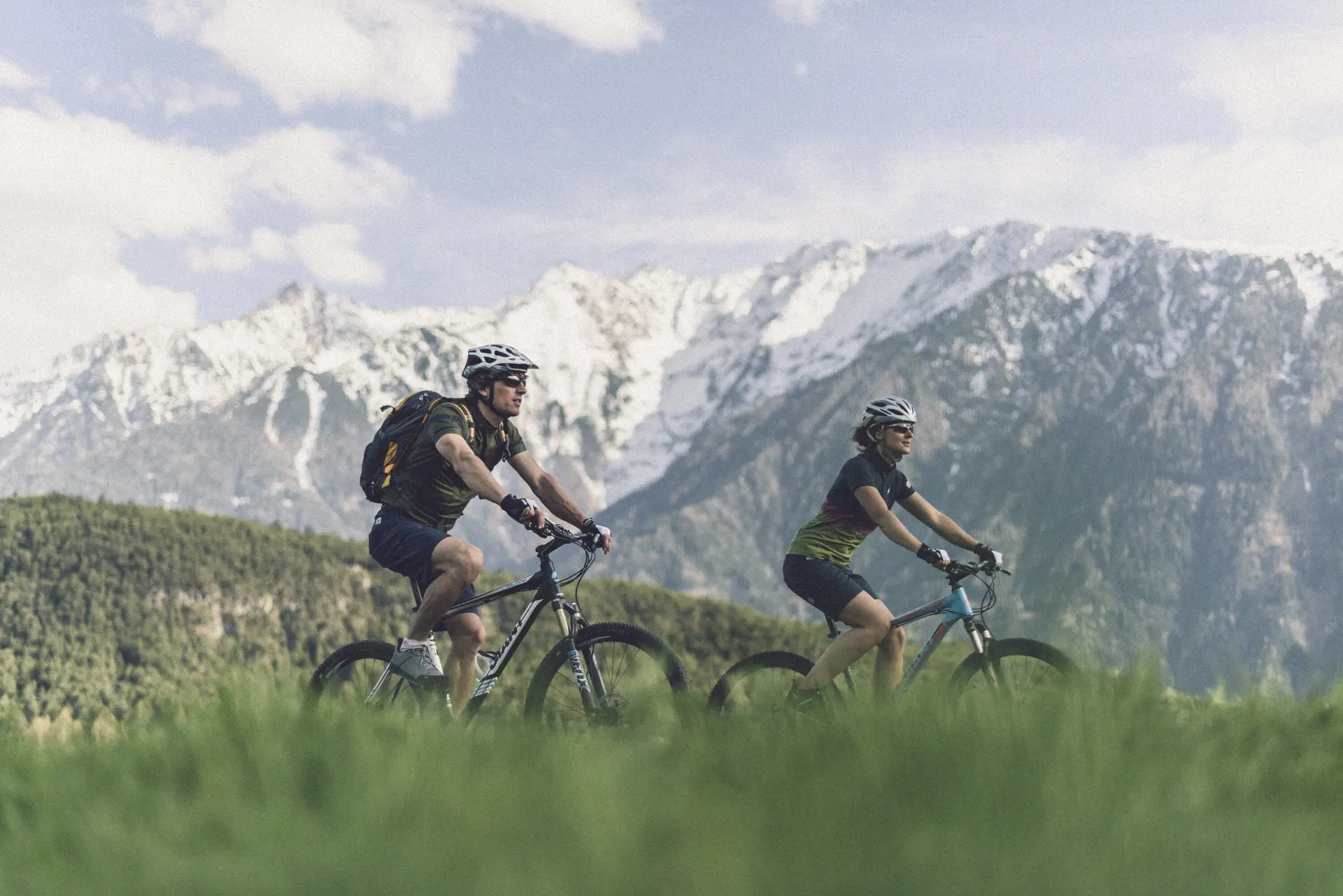 Zwei Personen fahren mit ihren Mountainbikes vor einer Bergkulisse. | © DAV/Wolfgang Ehn