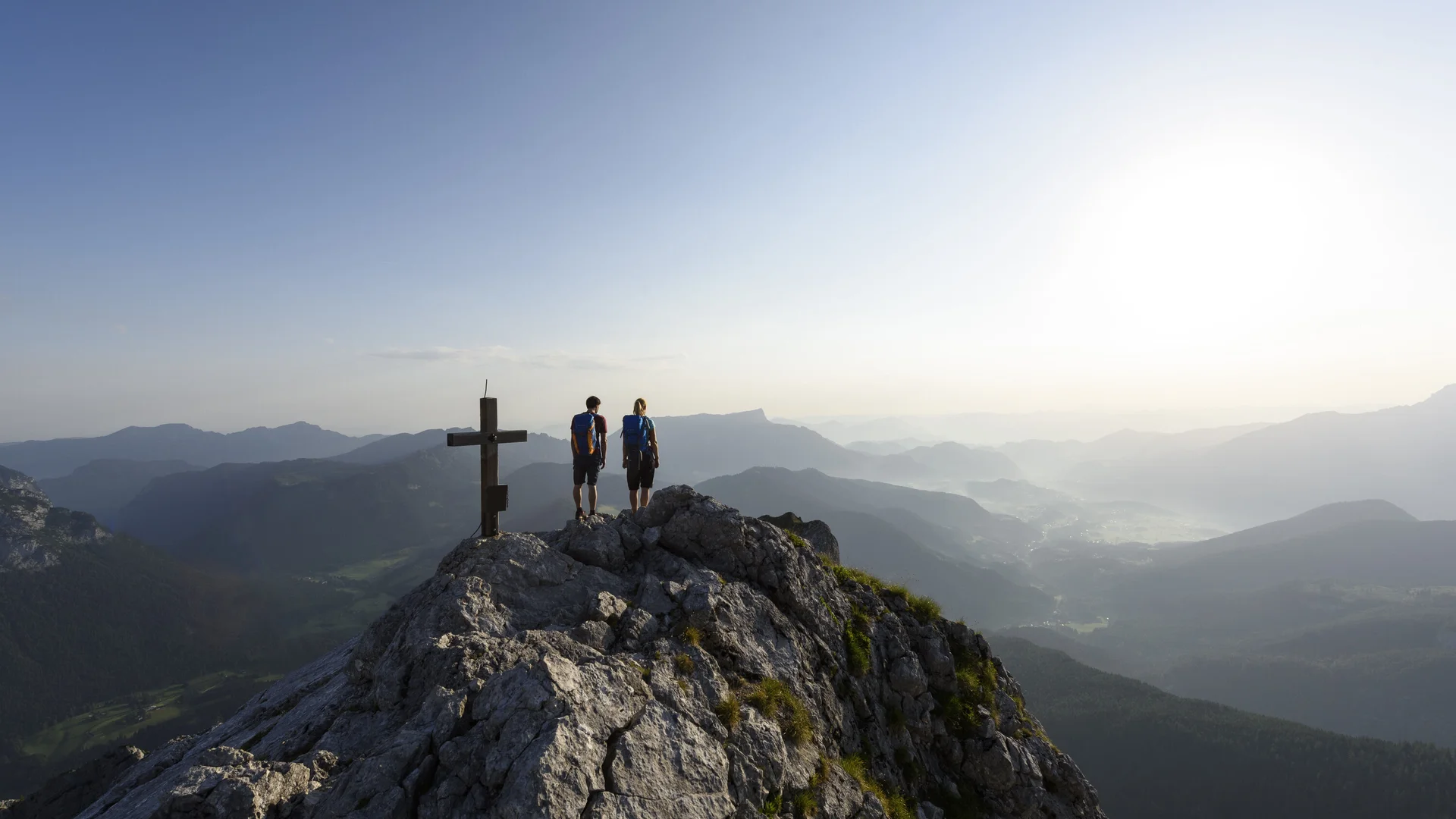 Zwei Wanderer auf einem Berggipfel mit Gipfelkreuz - aus der Ferne fotografiert | © DAV/Wolfgang Ehn